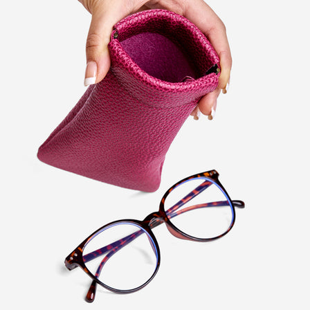 Cosmo | Model hand holding open leather glasses case with hidden metal spring closure above a pair of glasses