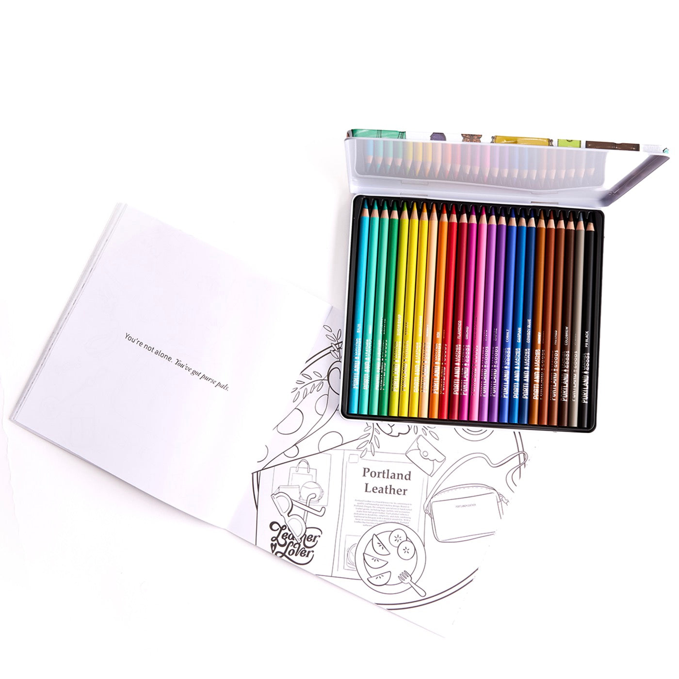 Set of colored pencils in a metal case with a coloring book on a white background.