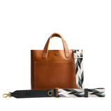 Moonstone | Patterned fabric and leather strap attached to leather purse on a white background