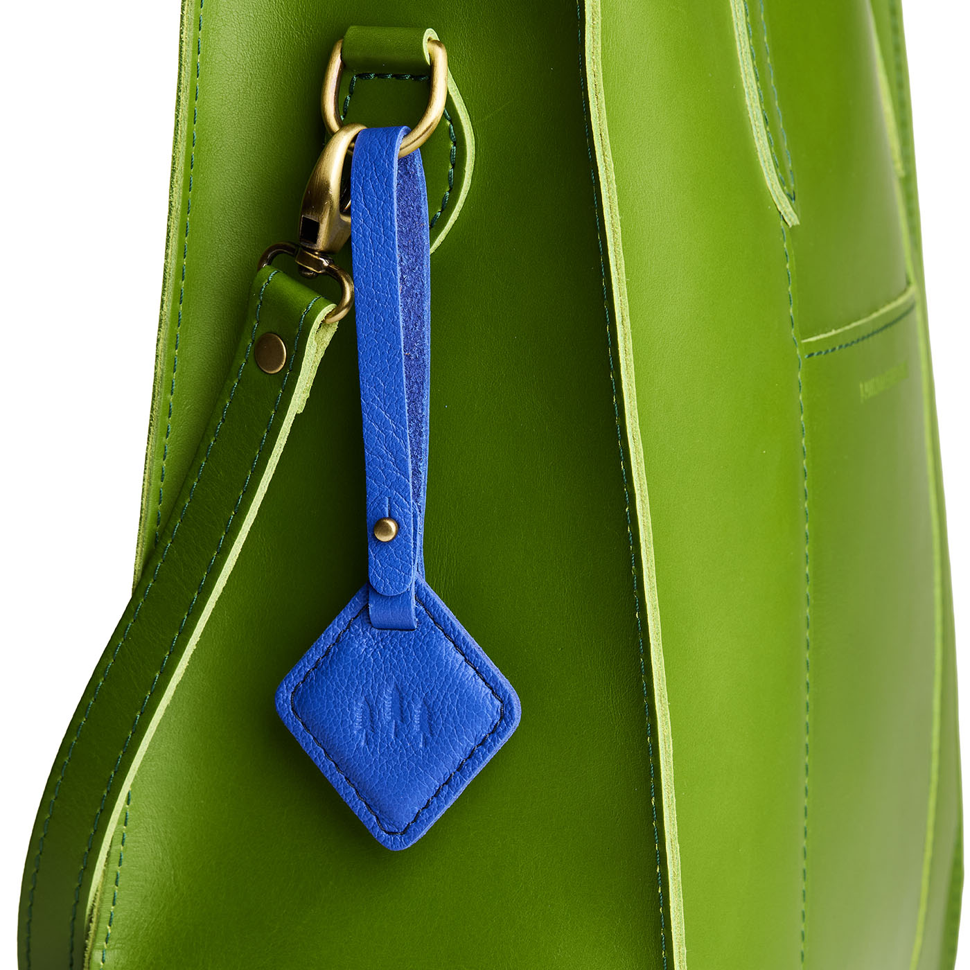 Astro Blue | Rhombus-shaped leather tag with a strap and debossed PLG design hanging from a green leather bag