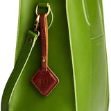 Nutmeg | Rhombus-shaped leather tag with a strap and debossed PLG design hanging from a green leather bag