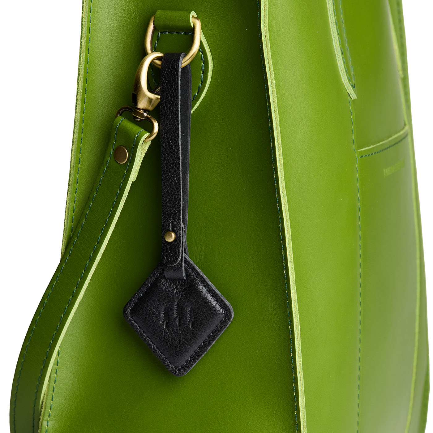 Pebbled--black | Rhombus-shaped leather tag with a strap and debossed PLG design hanging from a green leather bag