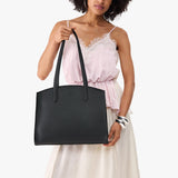 Black Large | Model carrying leather tote bag with handles, adjustable crossbody strap, and two back pockets