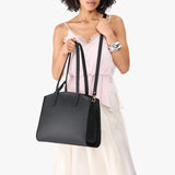 Black Large | Model carrying leather tote bag with handles, adjustable crossbody strap, and two back pockets