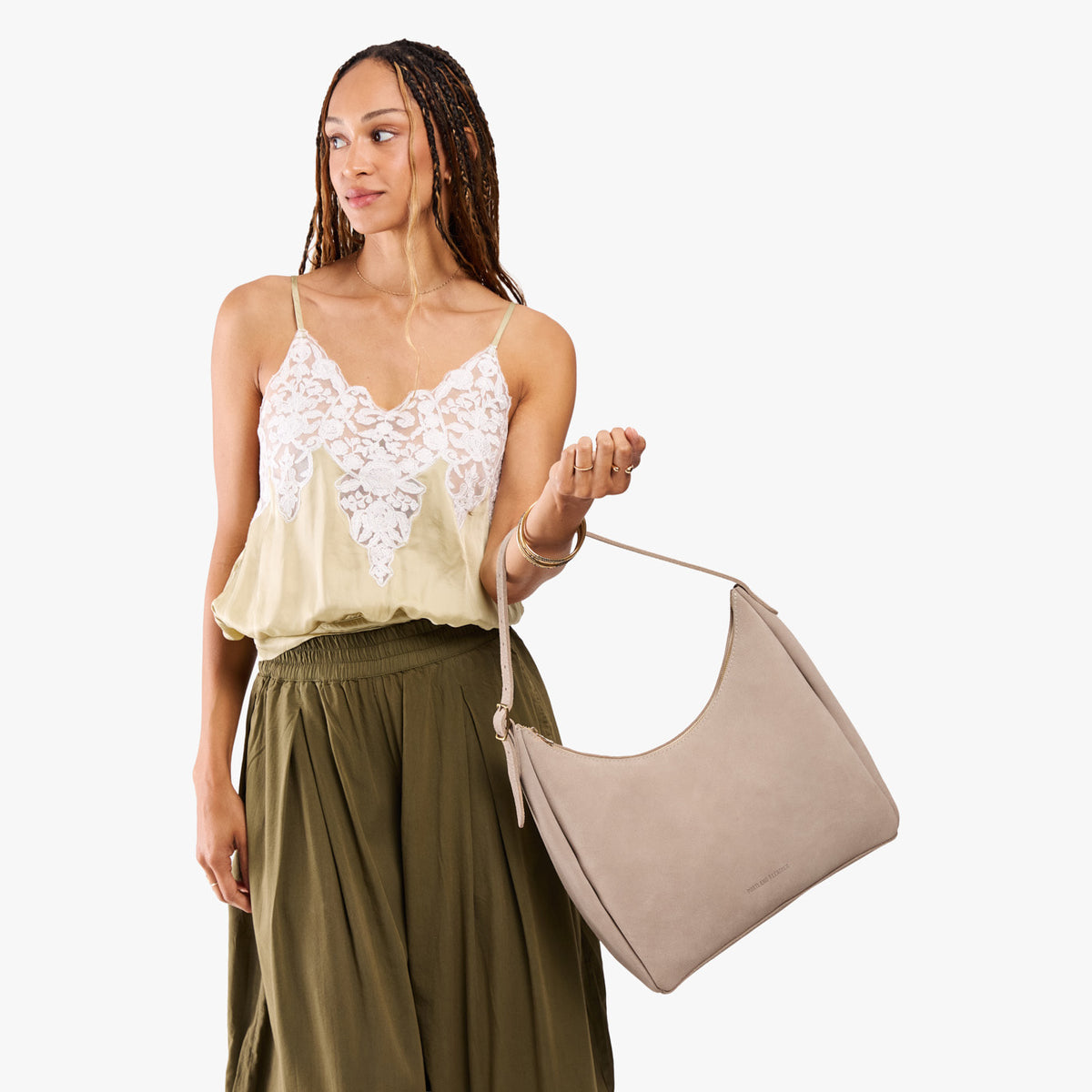 Taupe*Large | Model holding u-shaped, flat-bottomed leather shoulder bag with adjustable strap