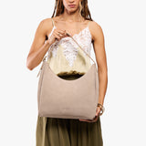 Taupe Large | Model holding u-shaped, flat-bottomed leather shoulder bag with adjustable strap