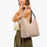 Taupe Large | Model holding u-shaped, flat-bottomed leather shoulder bag with adjustable strap