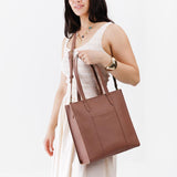 Sunkissed North/South | Model holding structured large tote bag with overlapping panels and crossbody strap