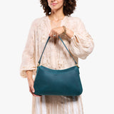 Westward Blue Large | Model holding a bean shaped shoulder bag with a zipper closure
