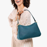Westward Blue Large | Model holding a bean shaped shoulder bag with a zipper closure