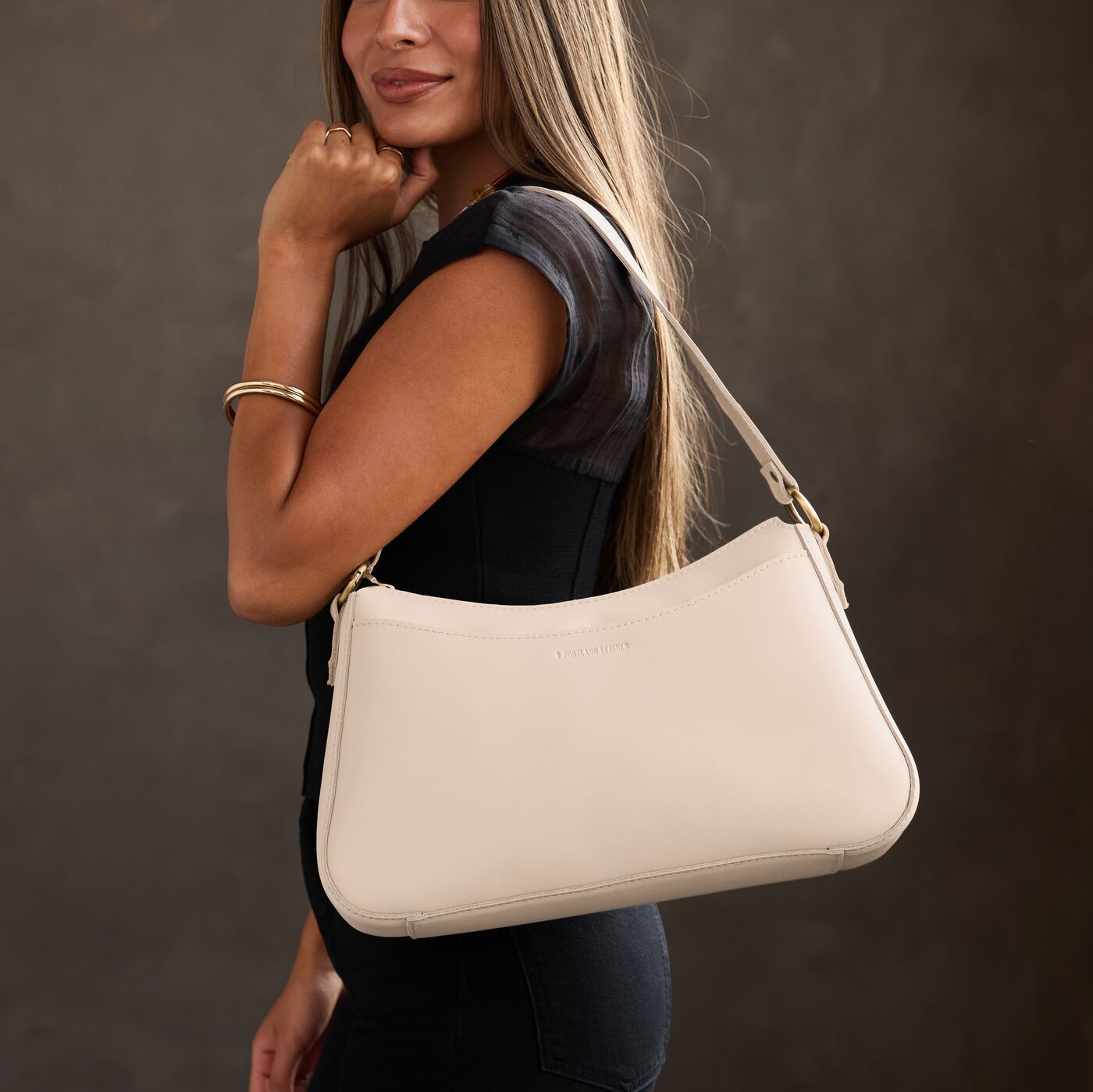 Bone*Large | Model holding a bean shaped shoulder bag with a zipper closure