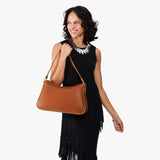 Honey Large | Model holding a bean shaped shoulder bag with a zipper closure