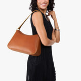 Honey Large | Model holding a petite bean shaped shoulder bag with a zipper closure
