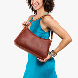 Nutmeg Large | Model holding a bean shaped shoulder bag with a zipper closure