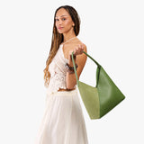 Dryland Green Large | Model holding mid-size shoulder bag with magnetic snap closure