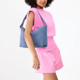 Denim Large | Model holding a Slouchy Shoulder Bag that has a zipper opening and three metal tree emblems