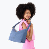 Denim Large | Model holding a Slouchy Shoulder Bag that has a zipper opening and three metal tree emblems