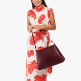 Cabernet Large | Model holding a triangular shoulder bag with antiqued brass finished 