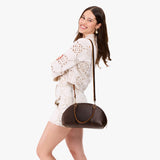 Coldbrew Small | Model holding a half circle crossbody bag with handles and removable crossbody strap 