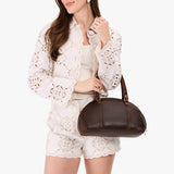 Coldbrew Small | Model holding a half circle crossbody bag with handles and removable crossbody strap 