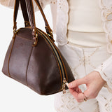 Coldbrew Small | Model holding a half circle crossbody bag with handles and removable crossbody strap 