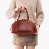 Nutmeg Small | Model holding a half circle crossbody bag with handles and removable crossbody strap 