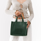 Aruba | Model holding structured mid-size tote bag with overlapping panels and crossbody strap