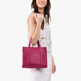 Cosmo | Model holding structured mid-size tote bag with overlapping panels and crossbody strap