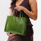 Green Apple | Model holding structured mid-size tote bag with overlapping panels and crossbody strap