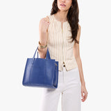 Molino Blue | Model carrying structured mid-size tote bag with overlapping panels and crossbody strap