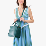 Sea Glass | Model holding structured mid-size tote bag with overlapping panels and crossbody strap