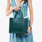 Sea Glass | Model holding structured mid-size tote bag with overlapping panels and crossbody strap