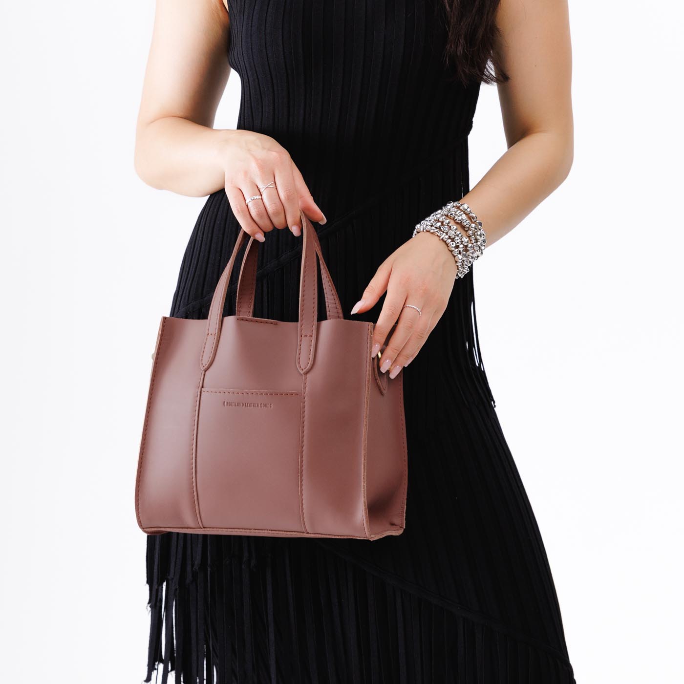 Sunkissed | Model holding structured mid-size tote bag with overlapping panels and crossbody strap