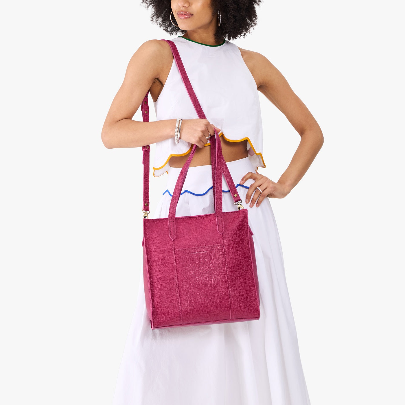 Cosmo*North/South | Model holding structured wide tote bag with overlapping panels and crossbody strap