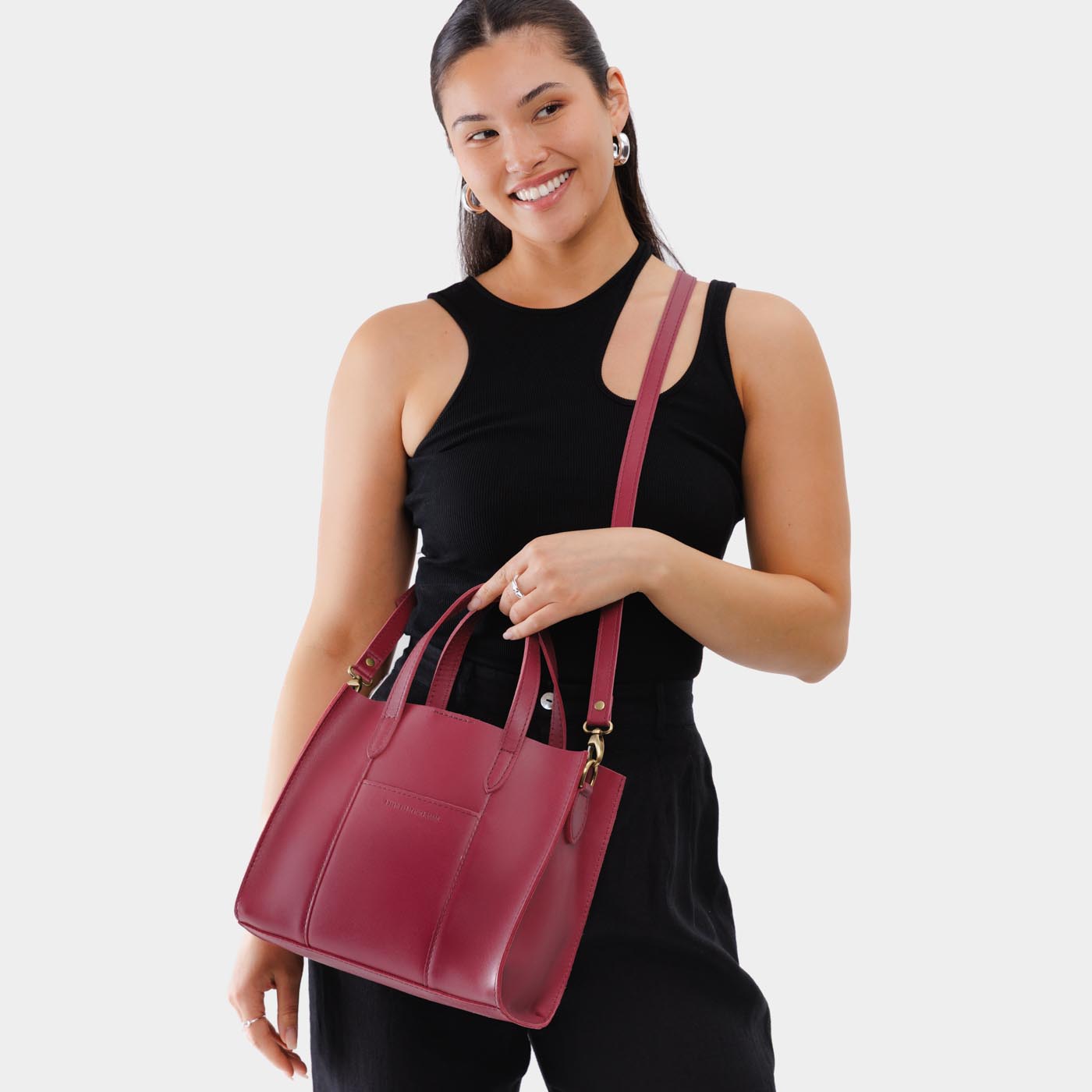 Berry Good | Model holding structured mid-size tote bag with overlapping panels and crossbody strap