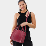 Berry Good | Model holding structured mid-size tote bag with overlapping panels and crossbody strap