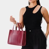 Berry Good | Model holding structured mid-size tote bag with overlapping panels and crossbody strap