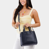 Night Owl | Model holding structured mid-size tote bag with overlapping panels and crossbody strap