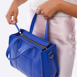 Astro Blue Zipper | Model holding structured mid-size tote bag with overlapping panels and crossbody strap