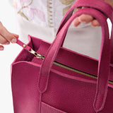 Cosmo Zipper | Model holding structured mid-size tote bag with overlapping panels and crossbody strap
