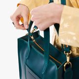 Westward Blue Zipper | Model holding structured mid-size tote bag with overlapping panels and crossbody strap