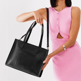 Black East/West | Model holding structured wide tote bag with overlapping panels and crossbody strap