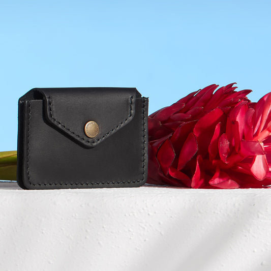 Black Lovebug Wallet next to a ginger flower