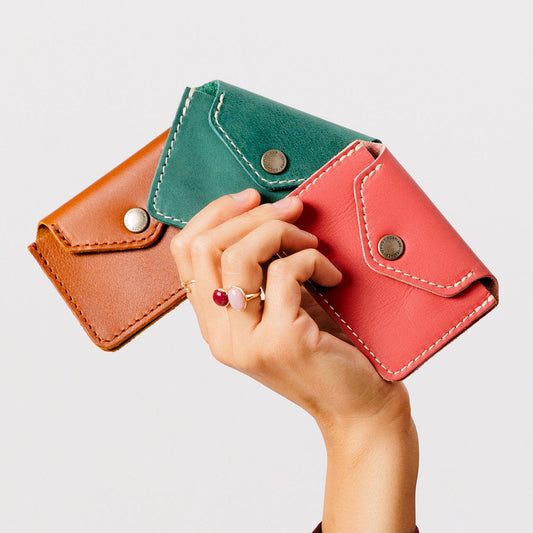 All Variants | Hand holding three different colored wallets with snap closures