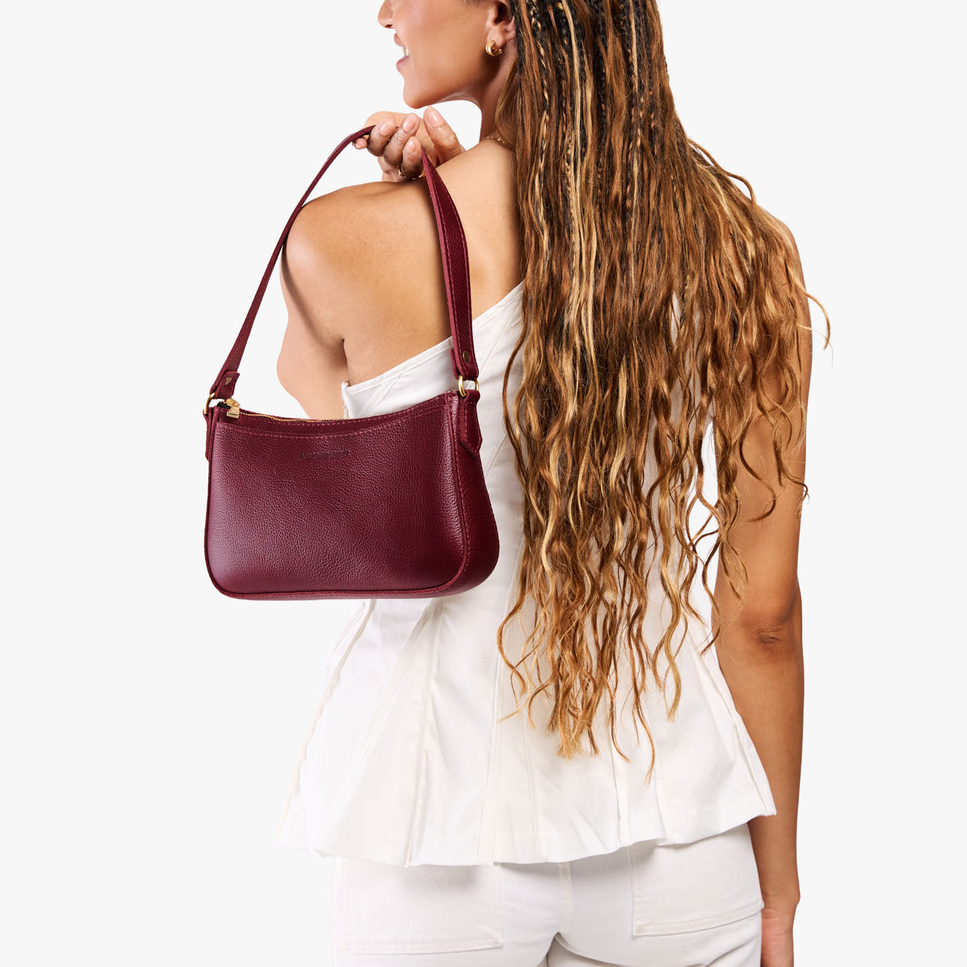 Cabernet*Small | Model carrying petite bean shaped shoulder bag with a zipper closure