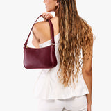 Cabernet Small | Model carrying petite bean shaped shoulder bag with a zipper closure