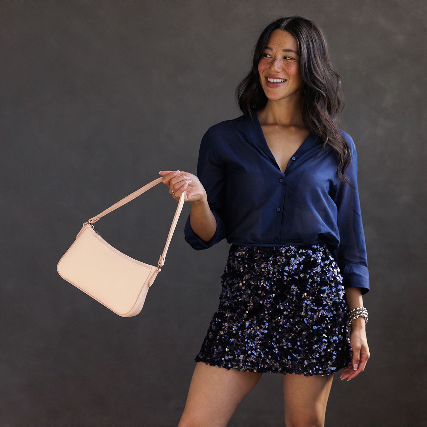 Moonflower | Model holding petite bean shaped shoulder bag with a zipper closure