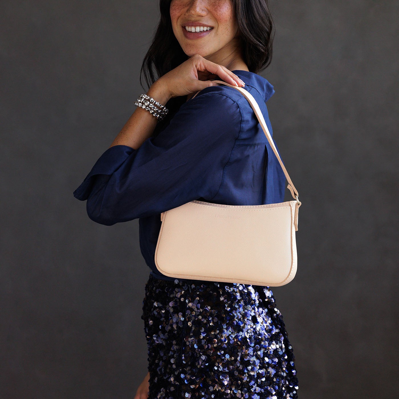 Moonflower | Model holding petite bean shaped shoulder bag with a zipper closure