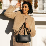 Pebbled--black | Model holding petite bean shaped shoulder bag with a zipper closure