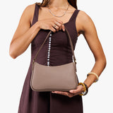 Sparrow Small | Model carrying petite bean shaped shoulder bag with a zipper closure
